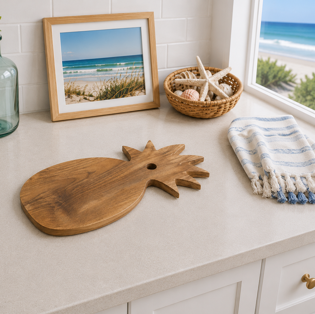 A wooden pineapple-shaped serving board with a hole in the center, styled on a light beige countertop in a bright kitchen setting.