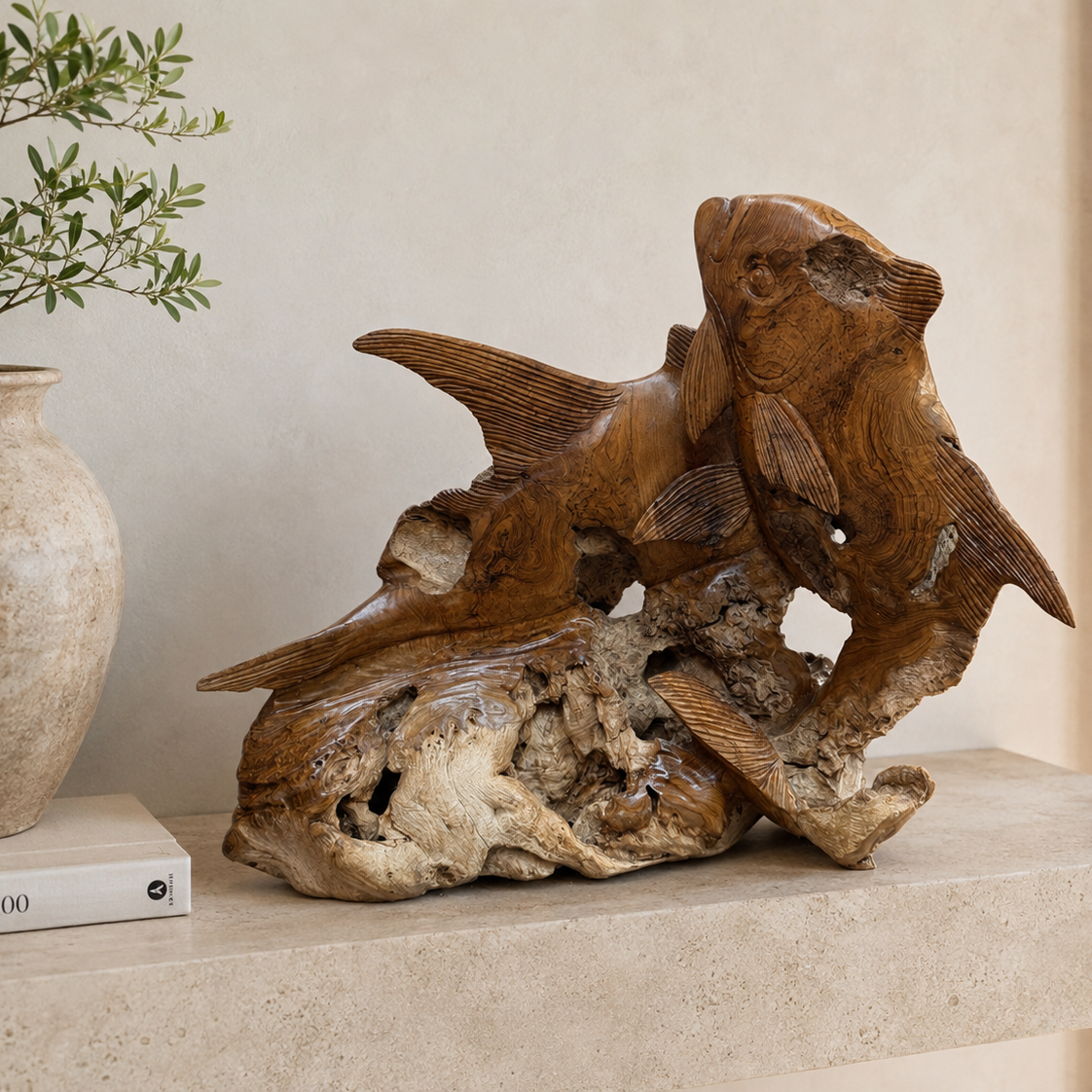 A carved wooden fish sculpture with realistic details and natural wood grain, displayed on a light stone shelf next to a beige ceramic vase with green leaves.