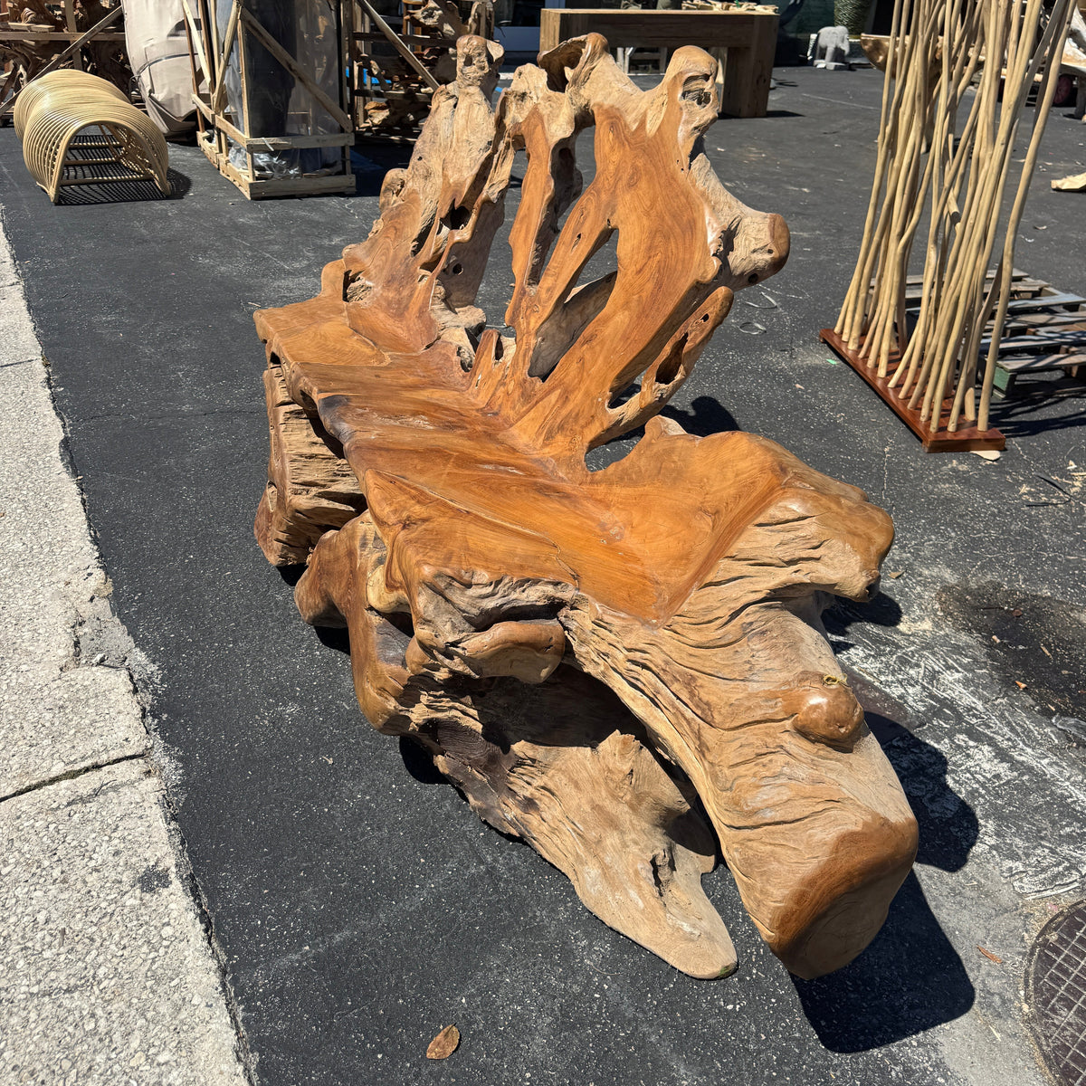 Wooden teak sculpture on a street with various items in the background