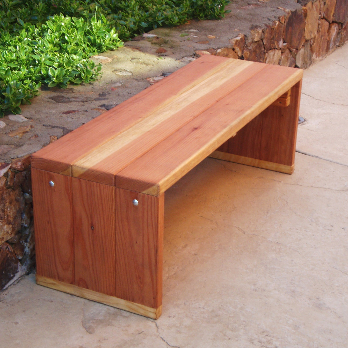 Wooden bench on a stone pathway with greenery
